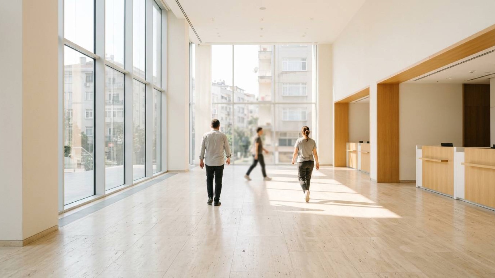A bright modern office lobby with tall windows and people crossing the floor
