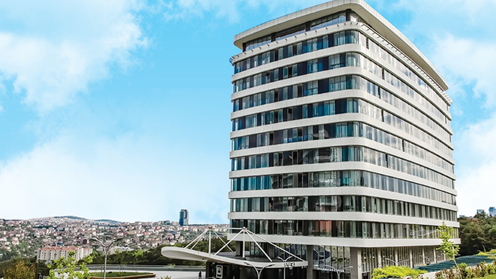 A curved white and glass office building seen from below against a clear sky